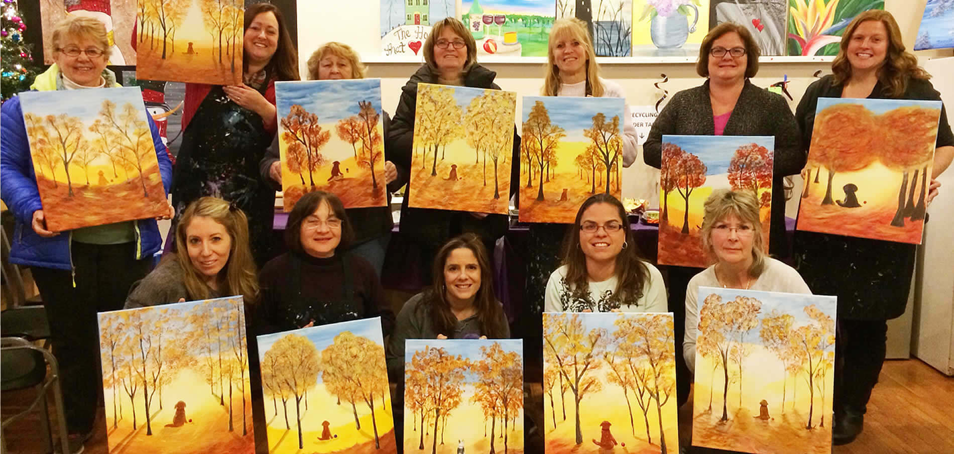 Group of women showing paintings of trees and dogs